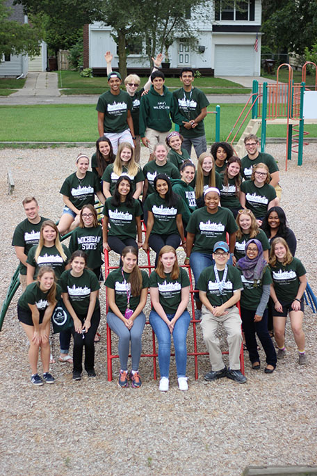 2017 HC IMPACT participants; students wearing green program T-shirts smiling at the camera on a playground toy structure