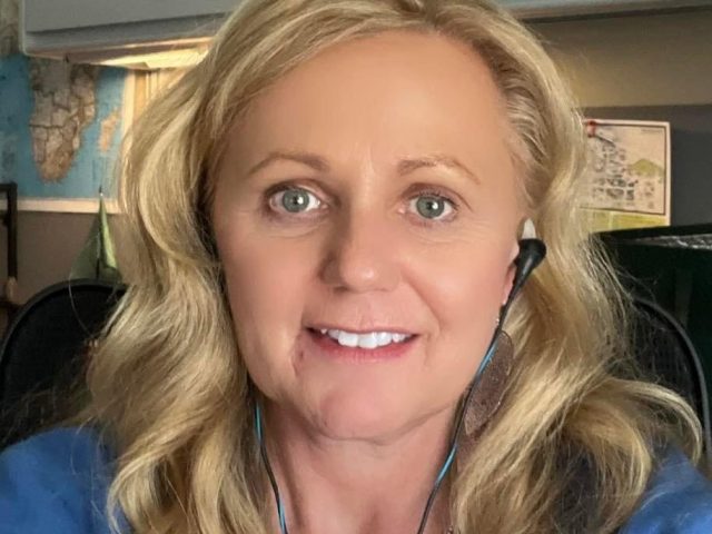 Lisa Hinds wearing headphones in an office and smiling