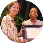 Photo of Dr. Constance Hunt and former HC Dean Jackson-Elmoore smiling at the camera holding an award plaque