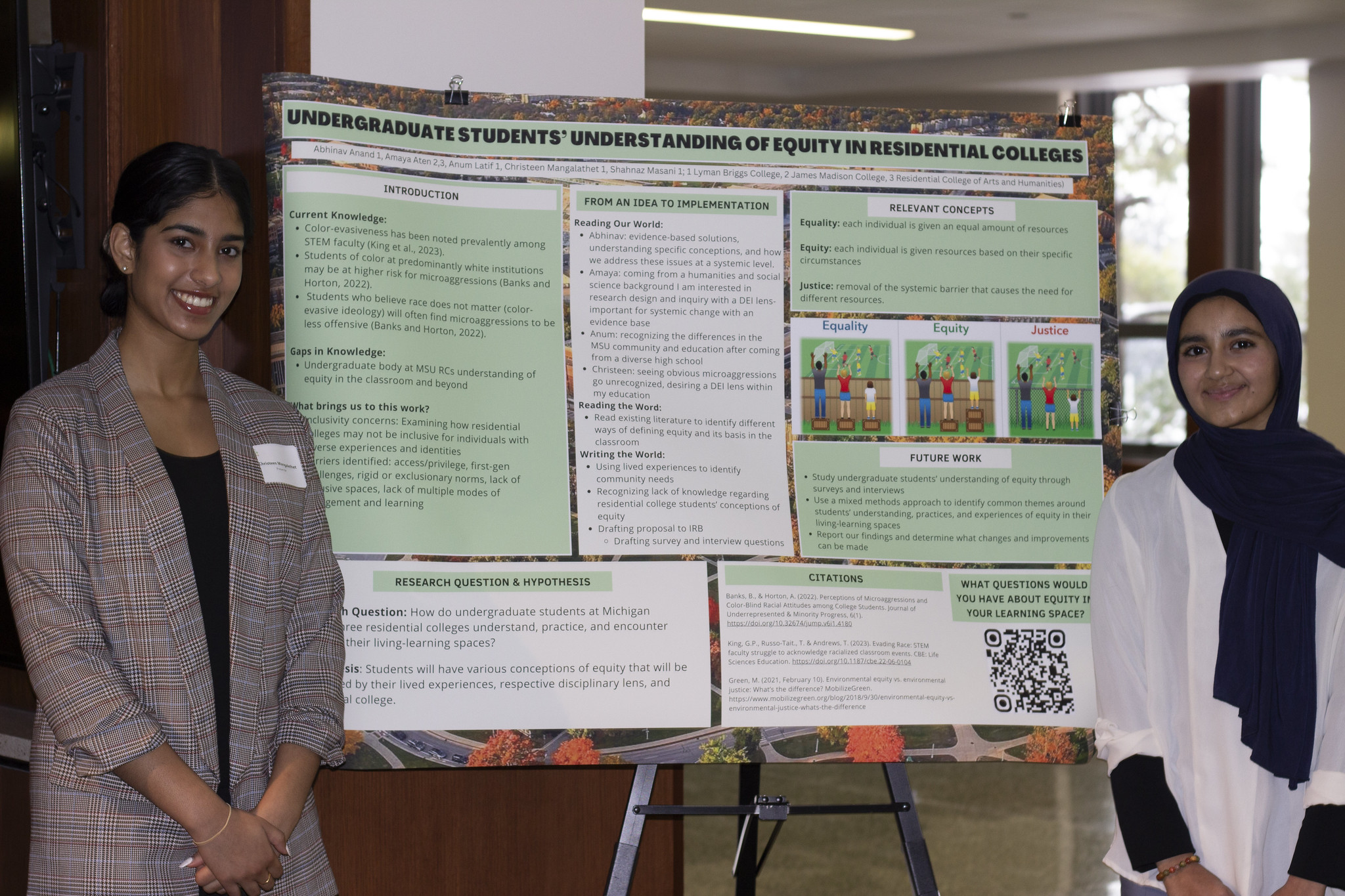 Two smiling students stand on either side of a light green and white poster titled "Understanding of Equity in Residential Colleges"