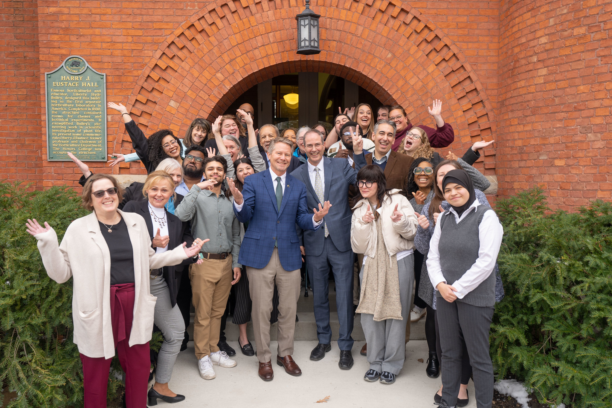 A group of people making silly poses in front of a red brick building