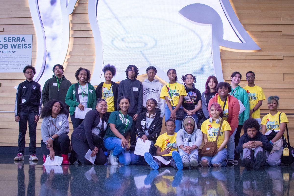 A group of students posing for a photo in front of a giant white Spartan head.