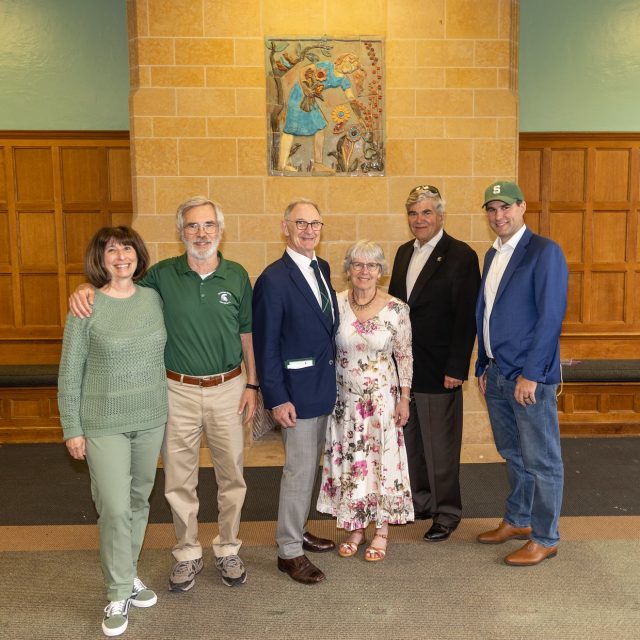 Members of the Porteous and Hamilton families stand and smile in the room that will become the new Grand Hall.