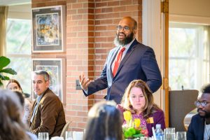 Interim Dean Glenn Chambers speaking to a group of people at an indoor dinner event.