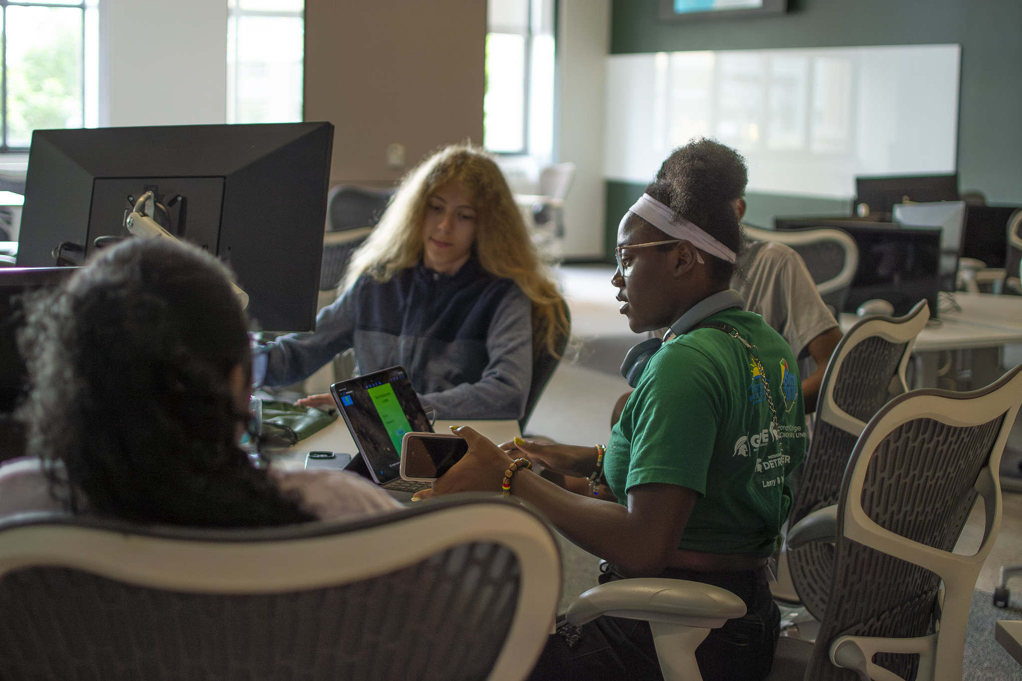 A group of students gather around a table at the Apple Developer Academy in Detroit to brainstorm app ideas.