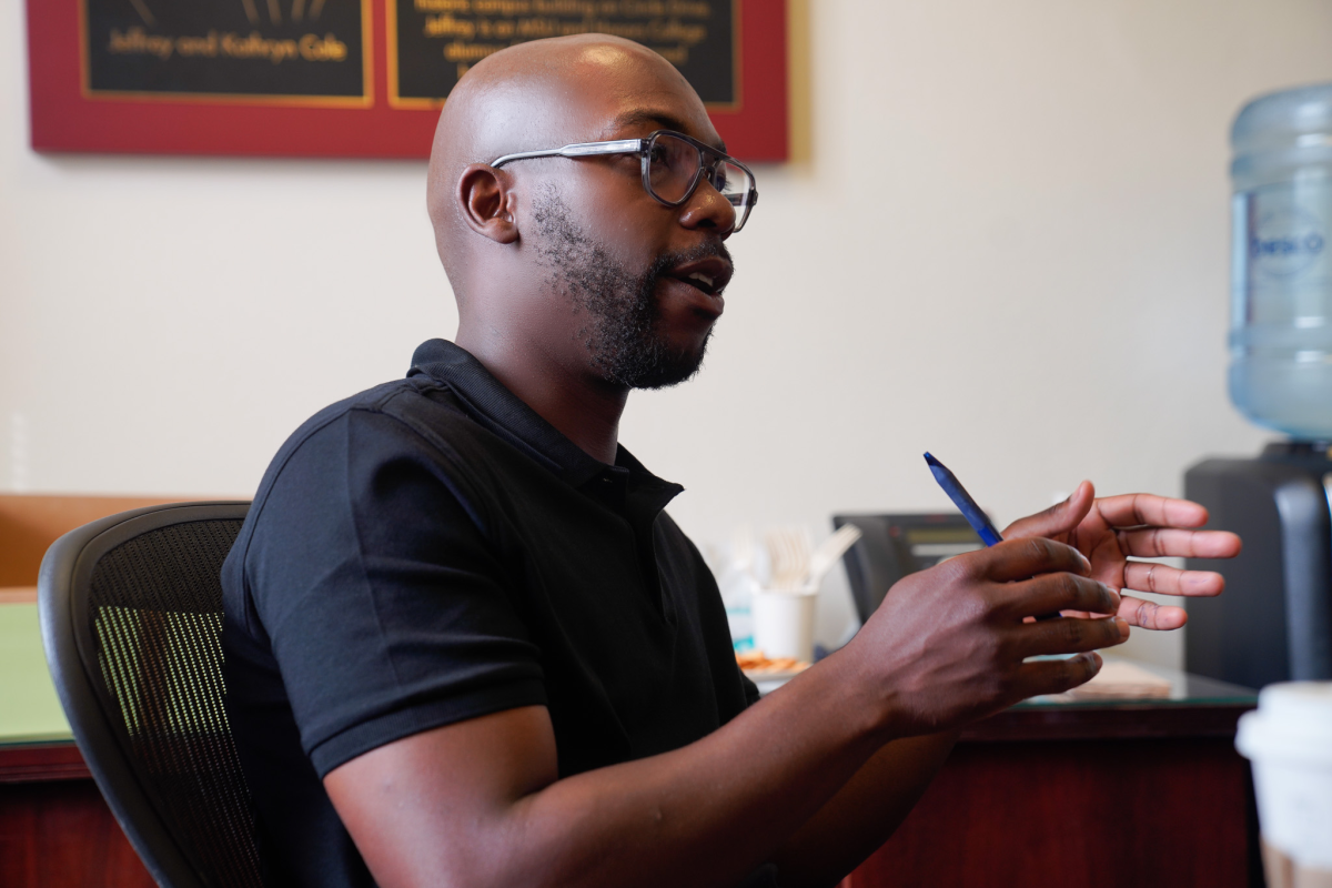 MSU alum Howard Akumiah sitting in a chair and speaking in the conference room at Eustace-Cole Hall