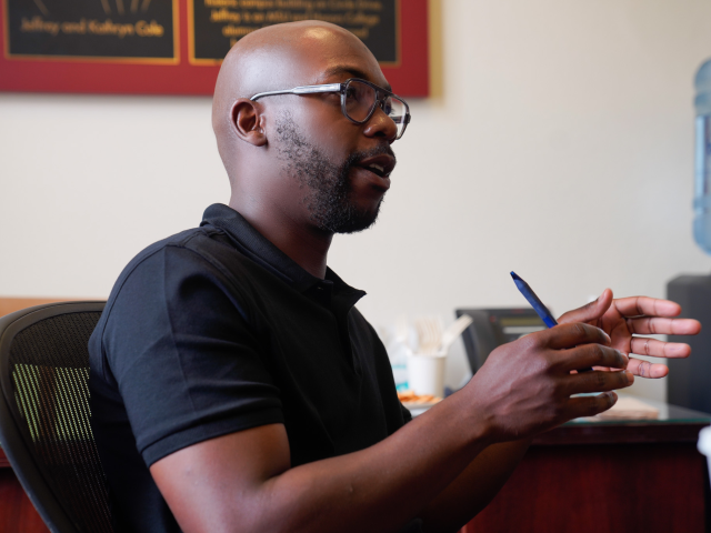 MSU alum Howard Akumiah sitting in a chair and speaking in the conference room at Eustace-Cole Hall