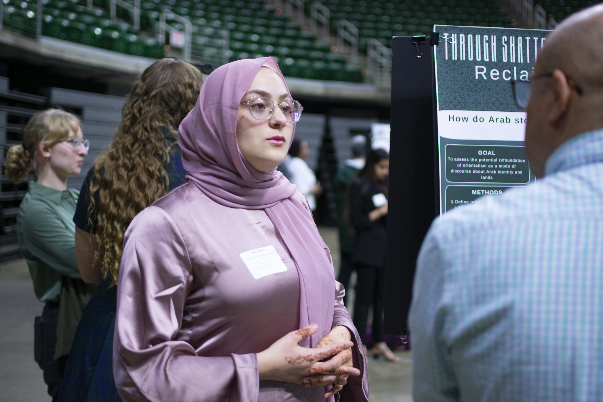 Alissa Hakim speaking to a guest about her research poster at UURAF