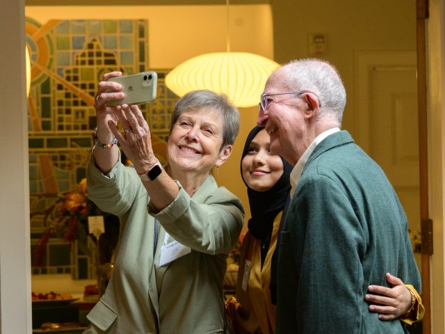 Two donors take a selfie with their scholarship recipient inside Cowles House.