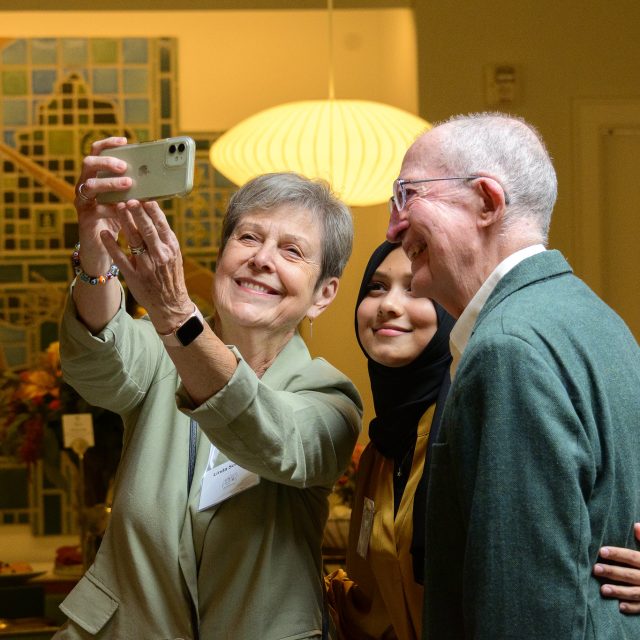 Two donors take a selfie with their scholarship recipient inside Cowles House.