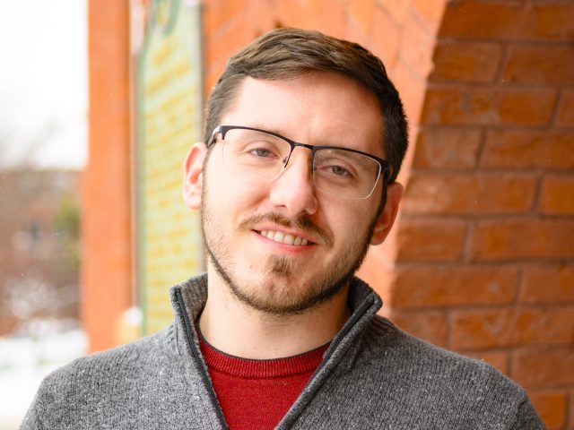 Portrait of Brett Binkowski in front of Eustace Cole Hall.