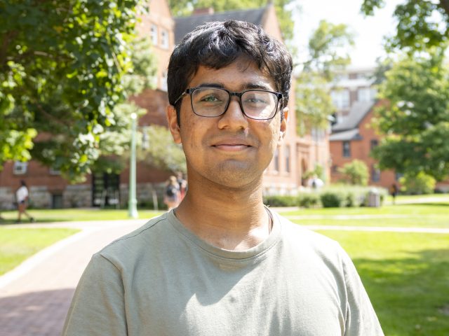 Lowell Monis in front of Eustace Cole Hall and neighboring buildings in the background.