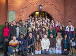 A large group of students stand smiling in front of Eustace Cole Hall.