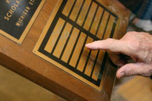 Seevers' hand is shown pointing to his name on a gold scholarship plaque.