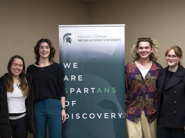 Four MLK Awardees stand together around a MSU branded banner that reads, "We Are Spartans of Discovery".