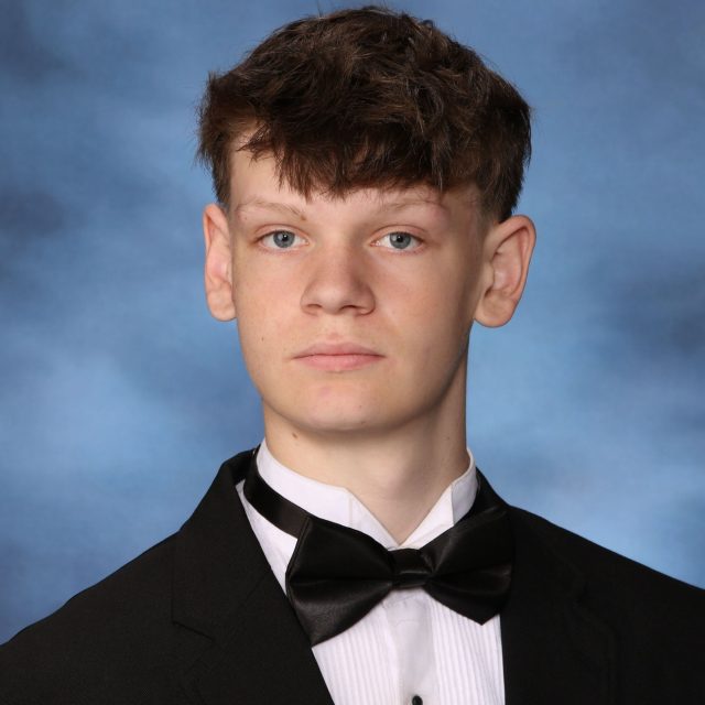 Billy McIntyre profile photo wearing a tuxedo in front of a neutral blue background.