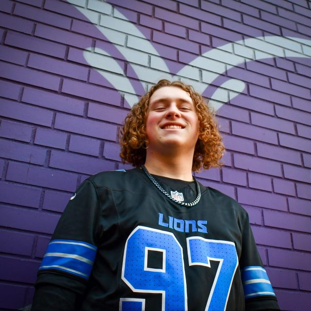 Kaiden Randol profile photo wearing a Detroit Lions jersey and standing in front of a purple and white brick wall.