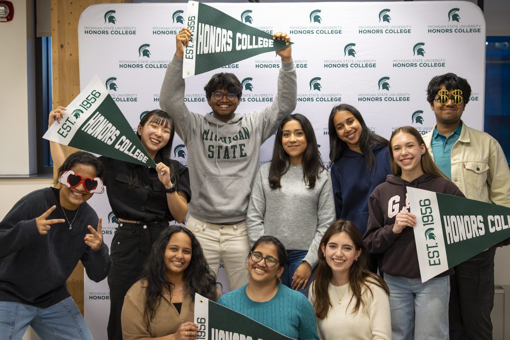 ISAB group photo with Green and White HC Backdrop and people holding HC Pennants.