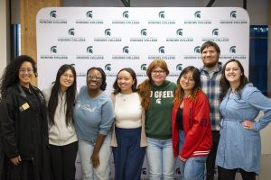 A group of people smiling to the camera, in front of a backdrop that says "Honors College".