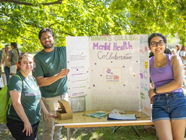 HC Mental Health Collaborative e-board posing for a picture with their poster in the middle of People's Park.