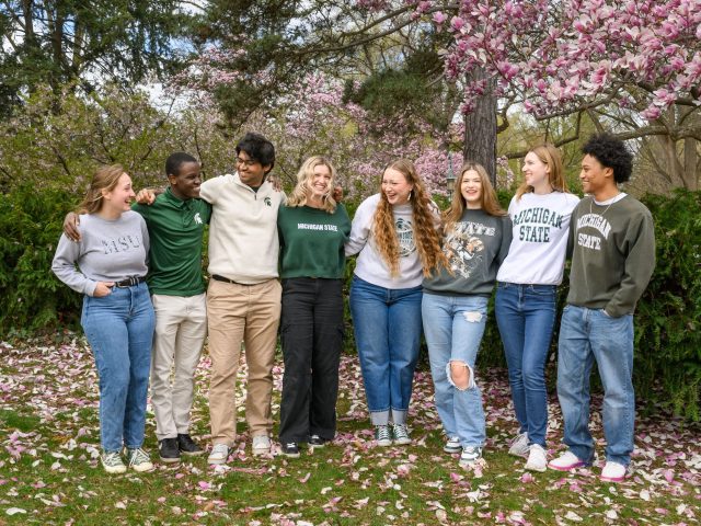 Group photo of the 8 Honors homecoming court members outside laughing together.