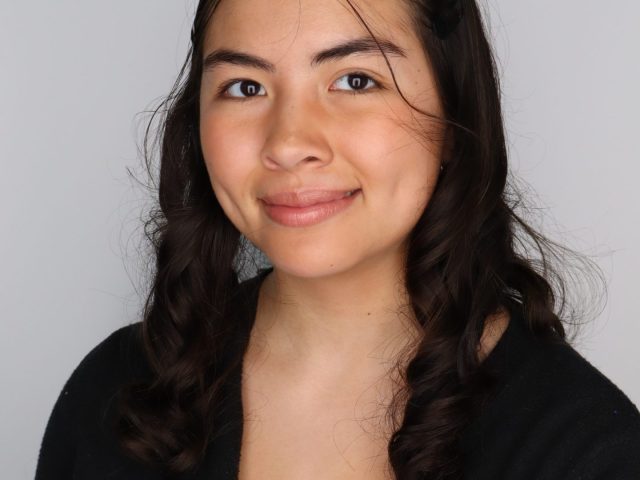 Professional image of Audrey Dayton softly smiling in a black top, against a neutral background.