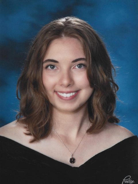 Professional image of incoming MSU Honors College student and University Distinguished Scholar Zora Key smiling in a black top against a blue and black gradient background.