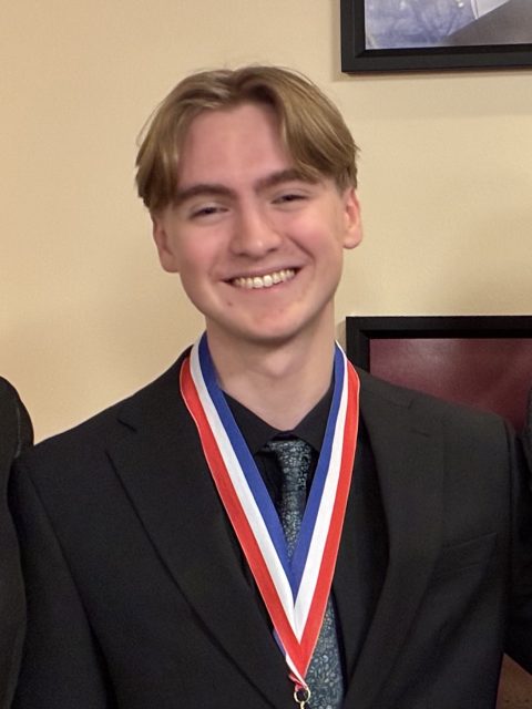 Image of incoming MSU Honors College student and Williams Scholar Jack Alton smiling in a black jacket and blue floral tie, wearing a red, white, and blue medal around the neck.
