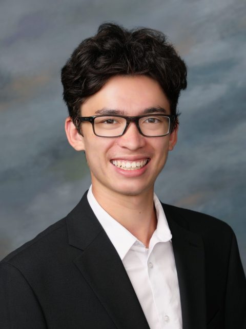 Professional image of incoming MSU Honors College student and Williams Scholar Nolan Booth smiling in a black suit jacket and white collared shirt against a grey gradient background.