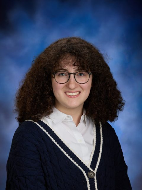 Professional image of incoming MSU Honors College student and Williams Scholar Lucky Cofone smiling in a blue and navy knit cardigan and white collared shirt against a blue gradient background.