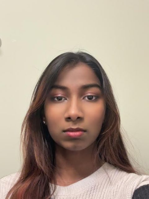 Image of incoming MSU Honors College student and Williams Scholar Mahathi Mathiyazhagan with a neutral expression against a blank wall, wearing a white and grey top.