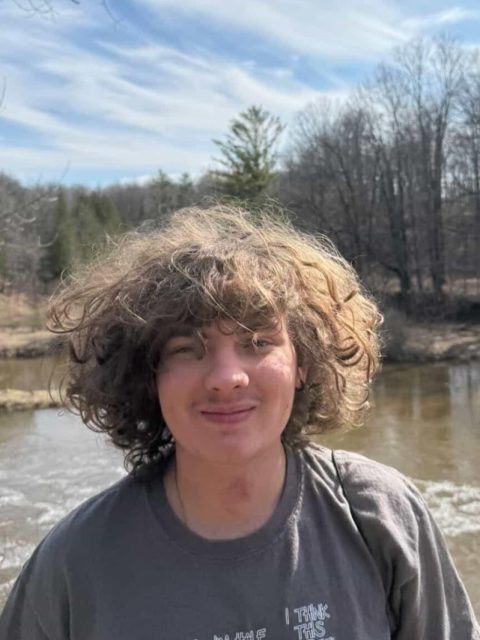 Image of incoming MSU Honors College student and Williams Scholar Jeff Soukhojak smiling in a grey t-shirt. A body of water and trees are in the background.