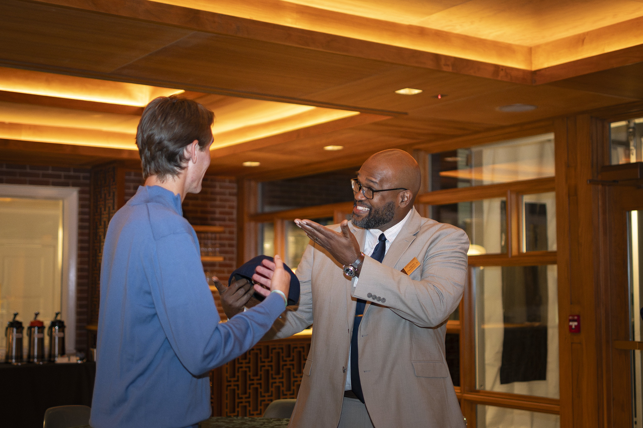 Honors College Dean Glenn Chambers in a tan suit talking to a student at Cowles House.
