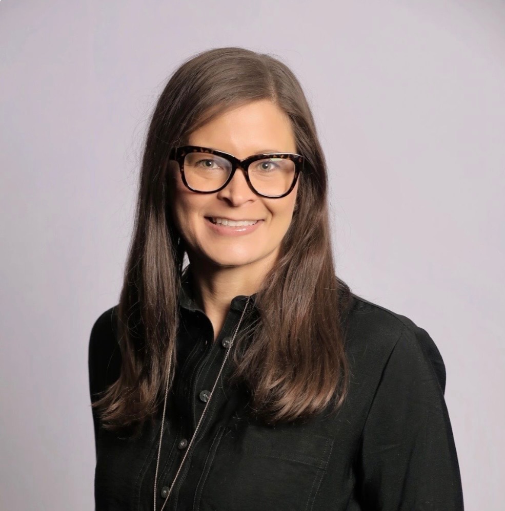 MSU Honors College alumna Jennifer Nichols smiling in a black button-up shirt.