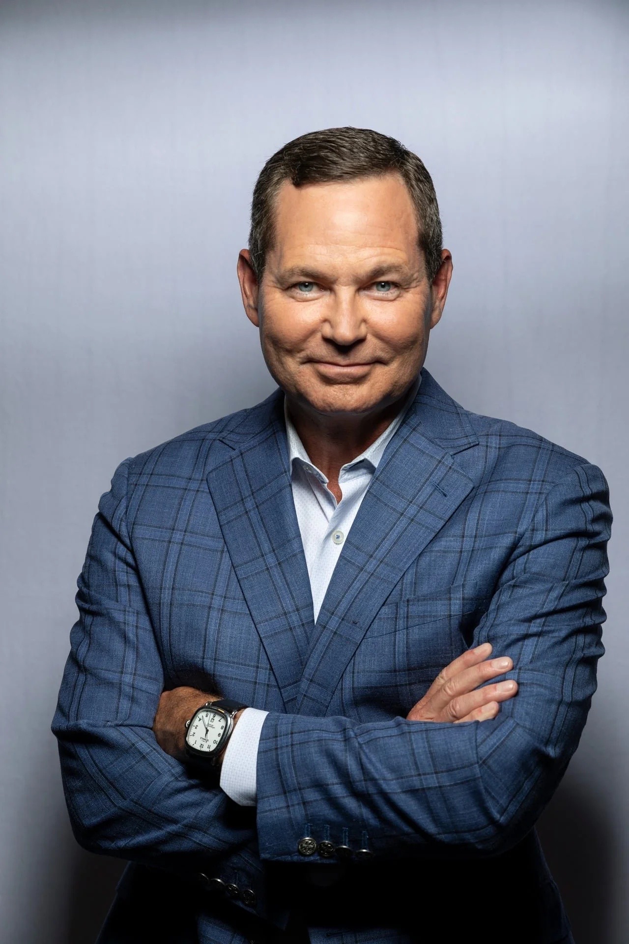Michigan State University Honors College alumnus Matt Elliott smiling with arms crossed, wearing a blue plaid suit.
