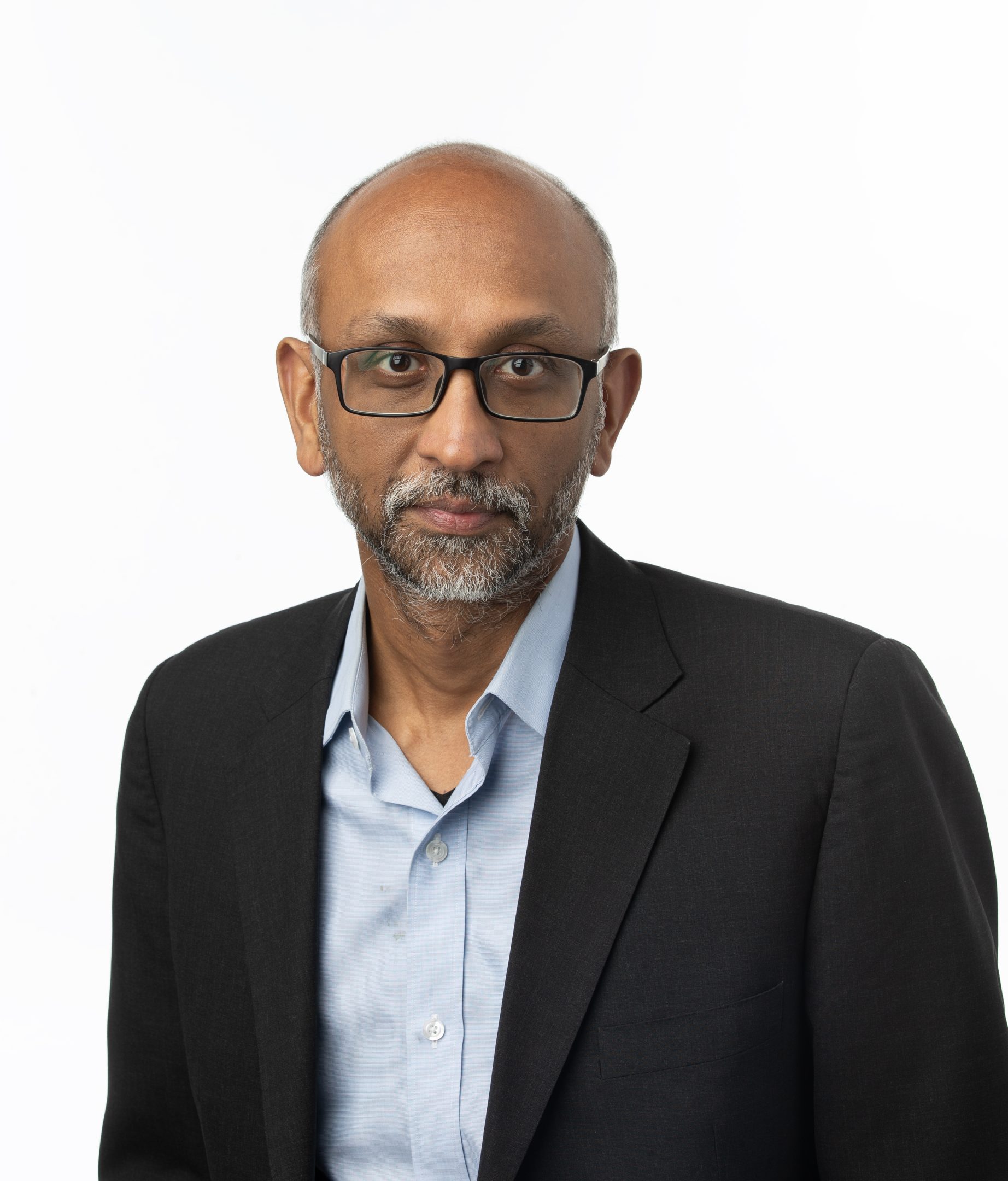 Honors College alumnus Vikas Bajaj in a black suit jacket and blue collared shirt.