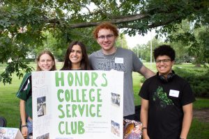 Photo of students standing in front of HCSC sign, smiling.