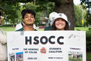 Photo of two students in front of HSOCC club sign. 