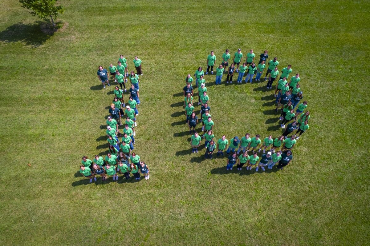 Aerial view of Honors College students, staff, and program partners for HC IMPACT arranged in the number 10. They are all wearing program t-shirts in various shades of green.