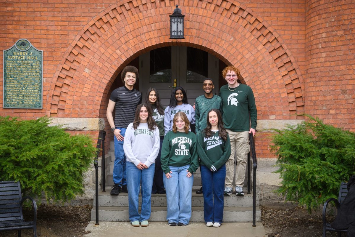 Honors College students of the 2026 Homecoming Court standing and smiling in front of Eustace-Cole Hall, wearing Michigan State attire.